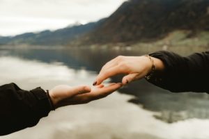 two people holding hands over a body of water